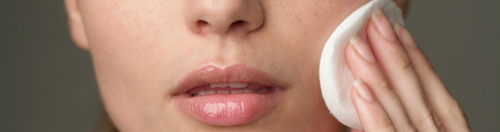 Young woman using a cotton pad for skincare, highlighting beauty routine.